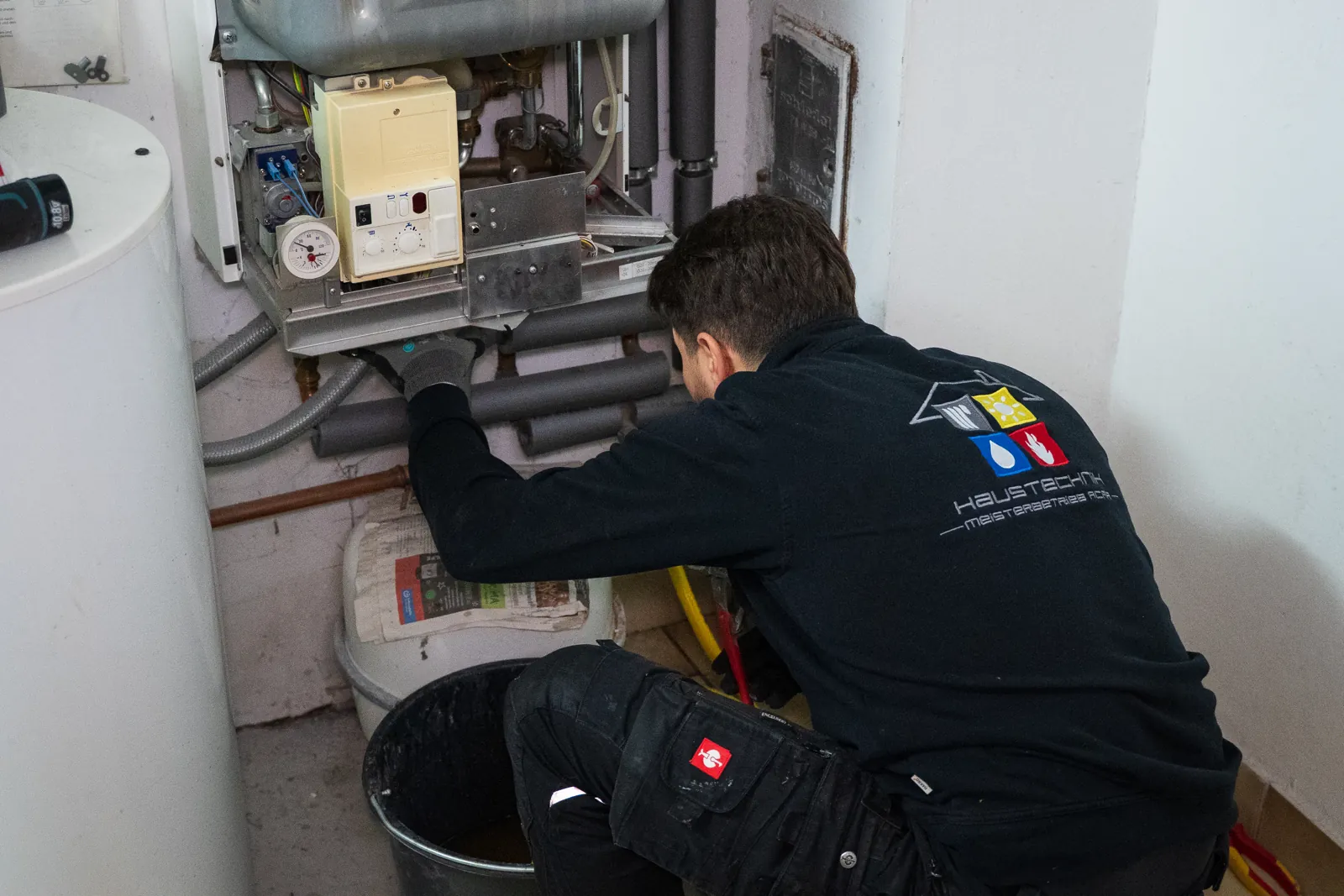 Monteur von Haustechnik Acar arbeitet an einer Heizungsanlage im Heizraum